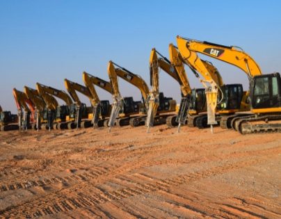 Row of tracked excavators on a desert site